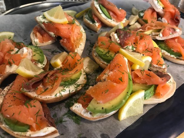 Platter of smoked salmon bagels, garnished with lemon and herbs.