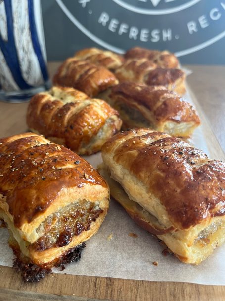 Golden-brown pastries filled with sausage on a wooden surface.
