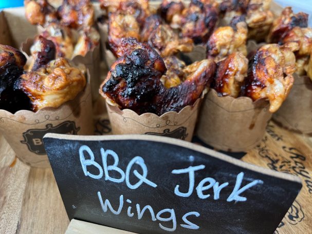 BBQ jerk chicken wings served in small brown paper cups.