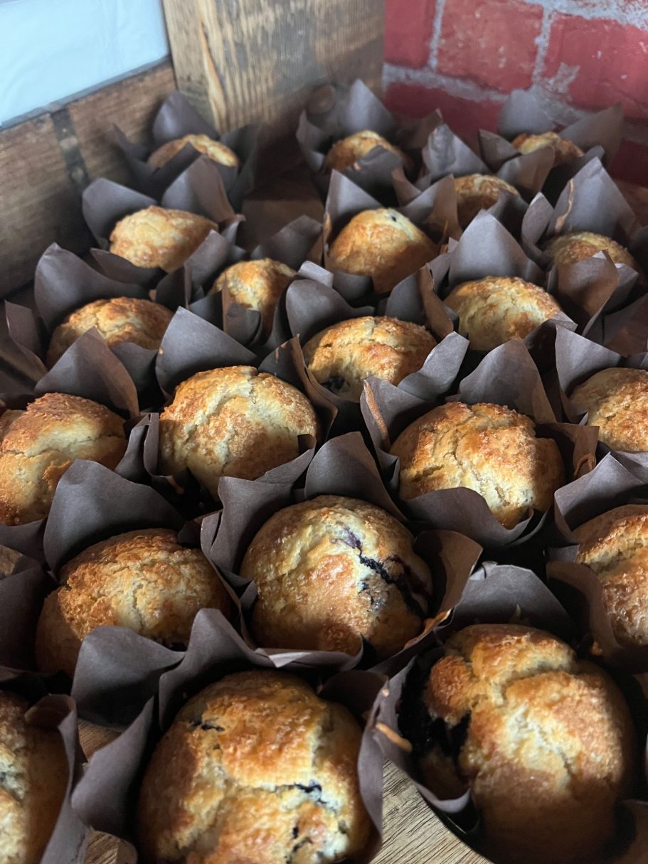 Freshly baked muffins in brown paper liners, arranged in a wooden box.