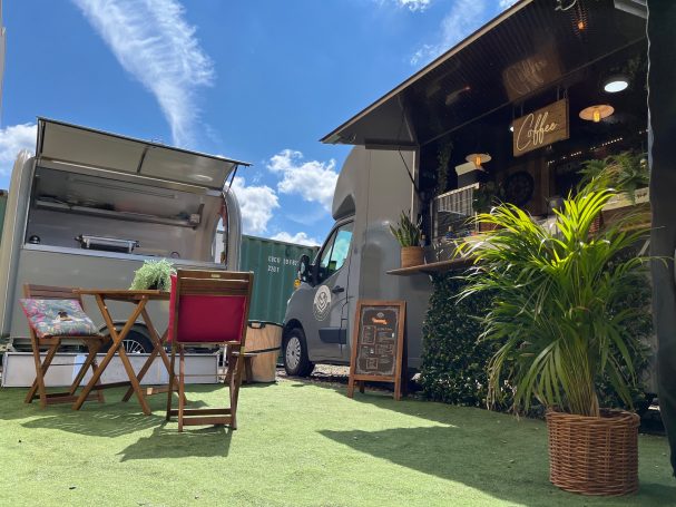 Food truck setup at the studio with a seating area, plants, and clear blue sky above.