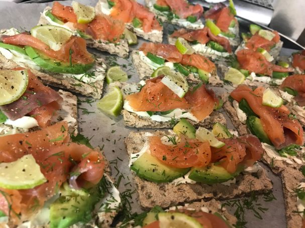 A platter of open-faced sandwiches topped with smoked salmon, cream cheese, and lime.