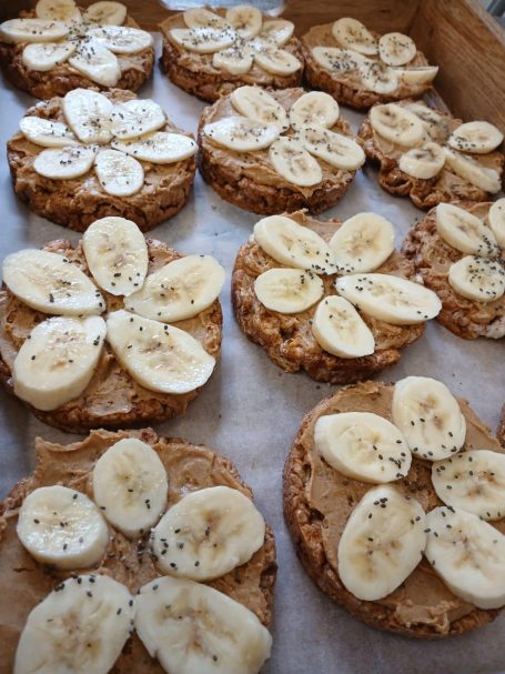 Circular rice cakes topped with peanut butter and decorative banana slices.