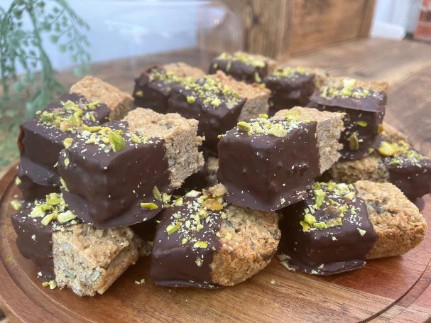 A stack of chocolate-covered fudge pieces garnished with pistachios.