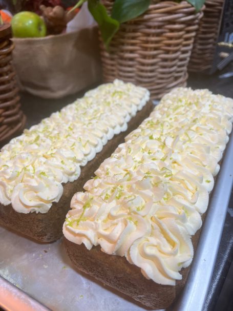 Two rectangular cakes topped with swirled cream and a drizzle of lime zest.