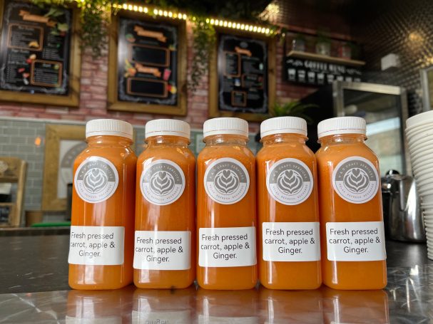 bottles of freshly pressed  juice lined up on a counter.